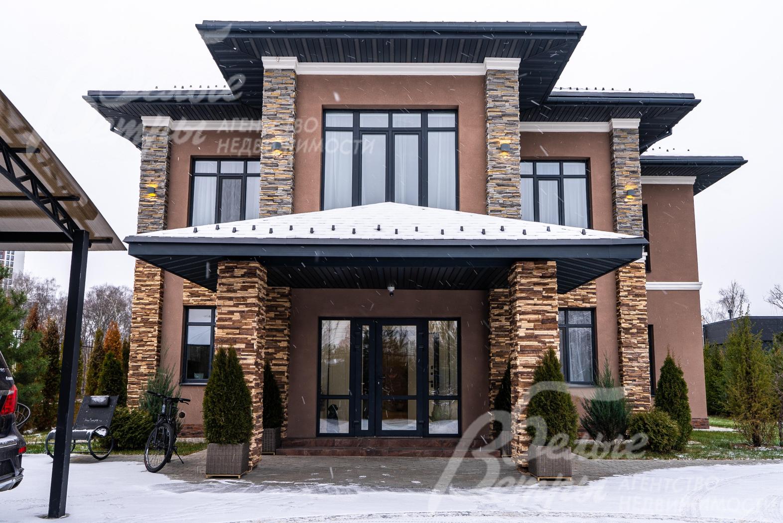 Фасад дома выполнен в тёплых коричневых тонах, крыльцо украшают колонны