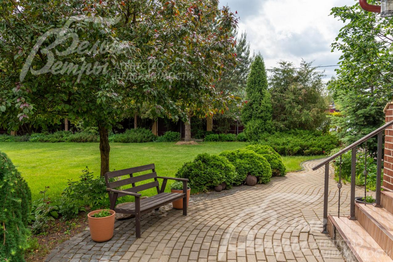 У входа в дом установлена скамейка для отдыха под деревом