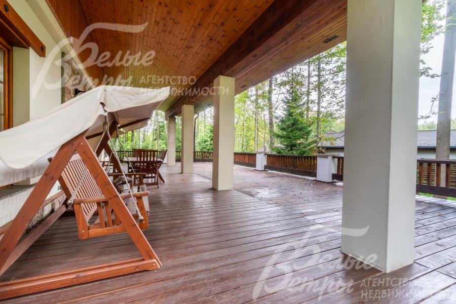 На просторной террасе - качели и садовая мебель