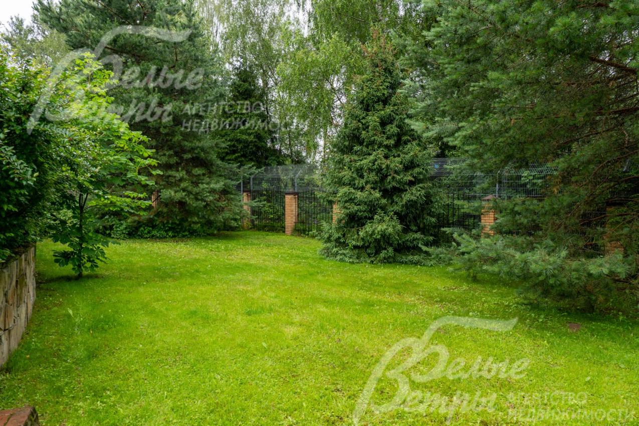 На участке выполнен проект паркового ландшафтного дизайна: высажен газон, взрослые хвойные деревья