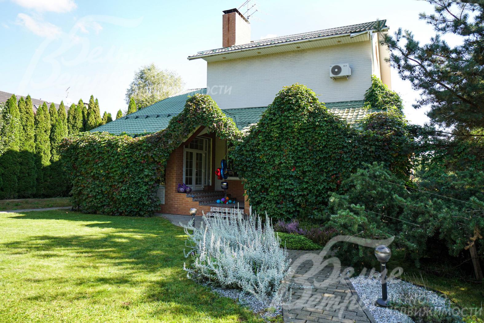 Один из входов в дом украшает декоративный виноград, на участке также высажен вереск