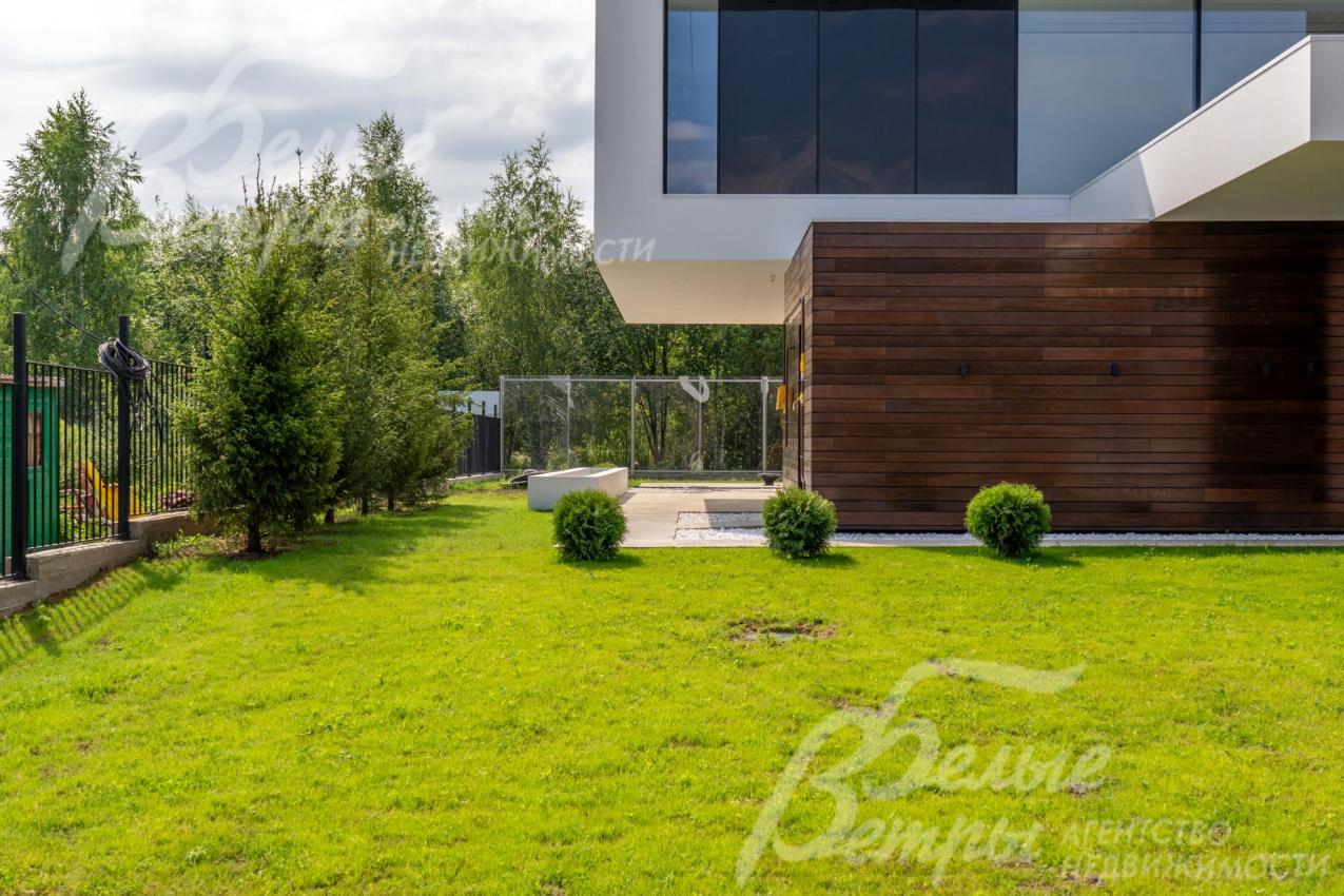 Дом стоит на просторном облагороженном участке с газоном и декоративными кустарниками