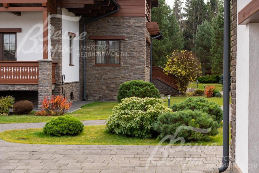 Часть фасада дома облицована искусственным камнем (справа - выход на участок из столовой)