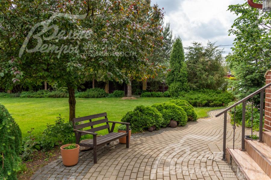 У входа в дом установлена скамейка для отдыха под деревом