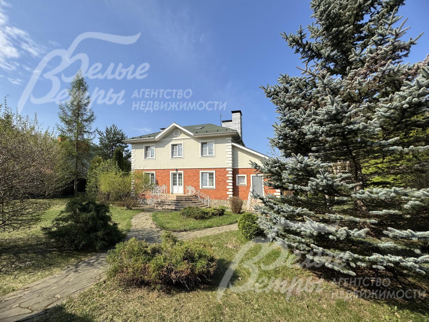 На зелёном просторном участке высажены взрослые деревья, ели, кустарники, цветники