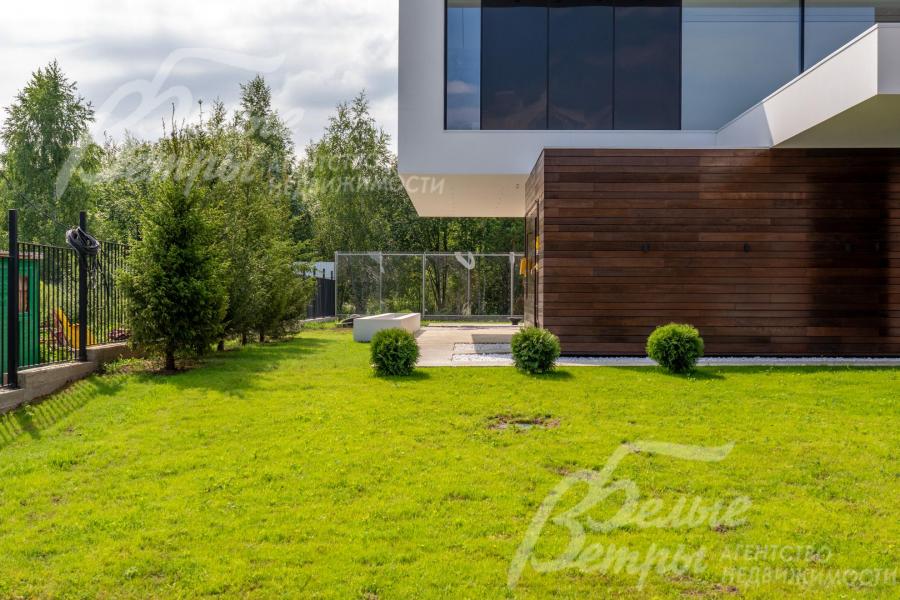 Дом стоит на просторном облагороженном участке с газоном и декоративными кустарниками