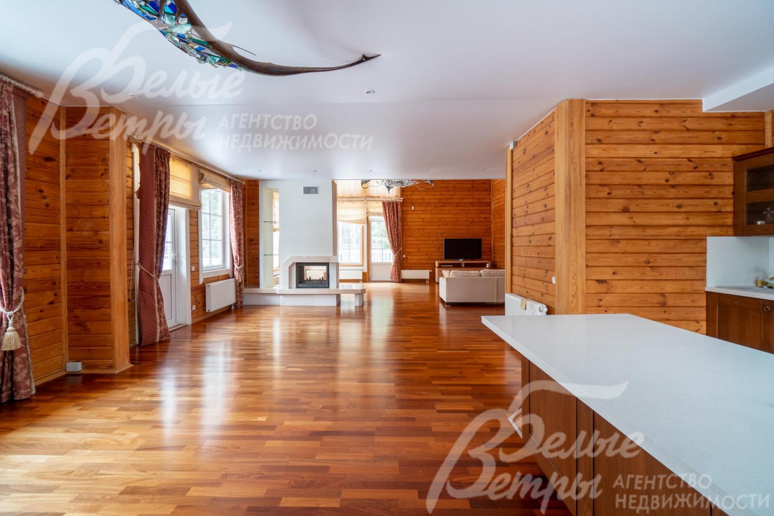 Вход из гостиной в кухню-столовую в основном доме через широкий портал, стены оформлены в едином стиле