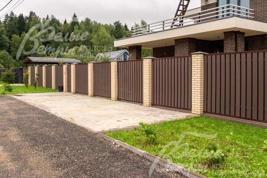 Участок огорожен забором на кирпичных столбах высотой 2 м 