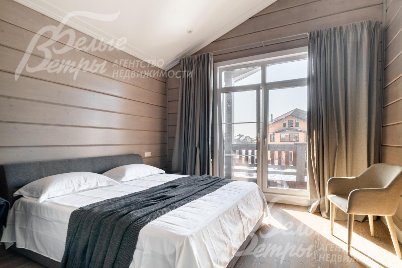 Одна из спален на втором этаже: на полу — инженерная доска. Интерьер оформлен в сдержанном стиле с благородной фактурой натурального дерева