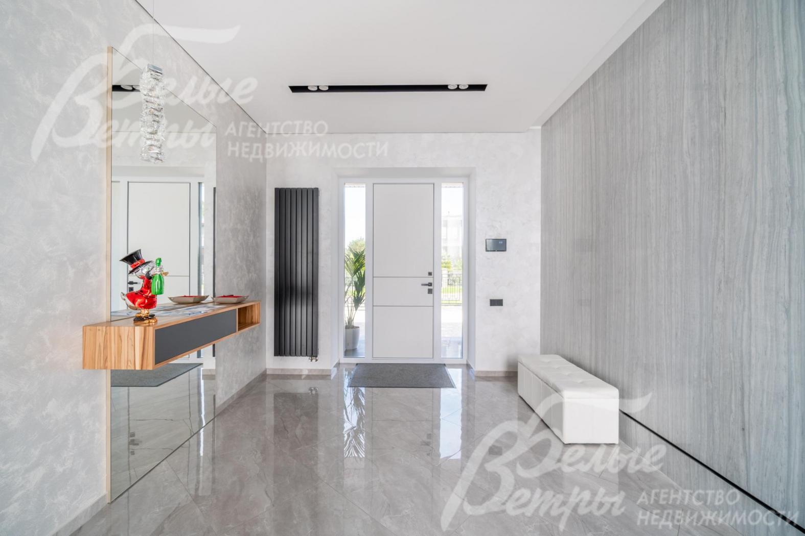 Просторный холл в светло-серых оттенках, на полу - широкоформатный керамогранит - мрамор с водяным подогревом