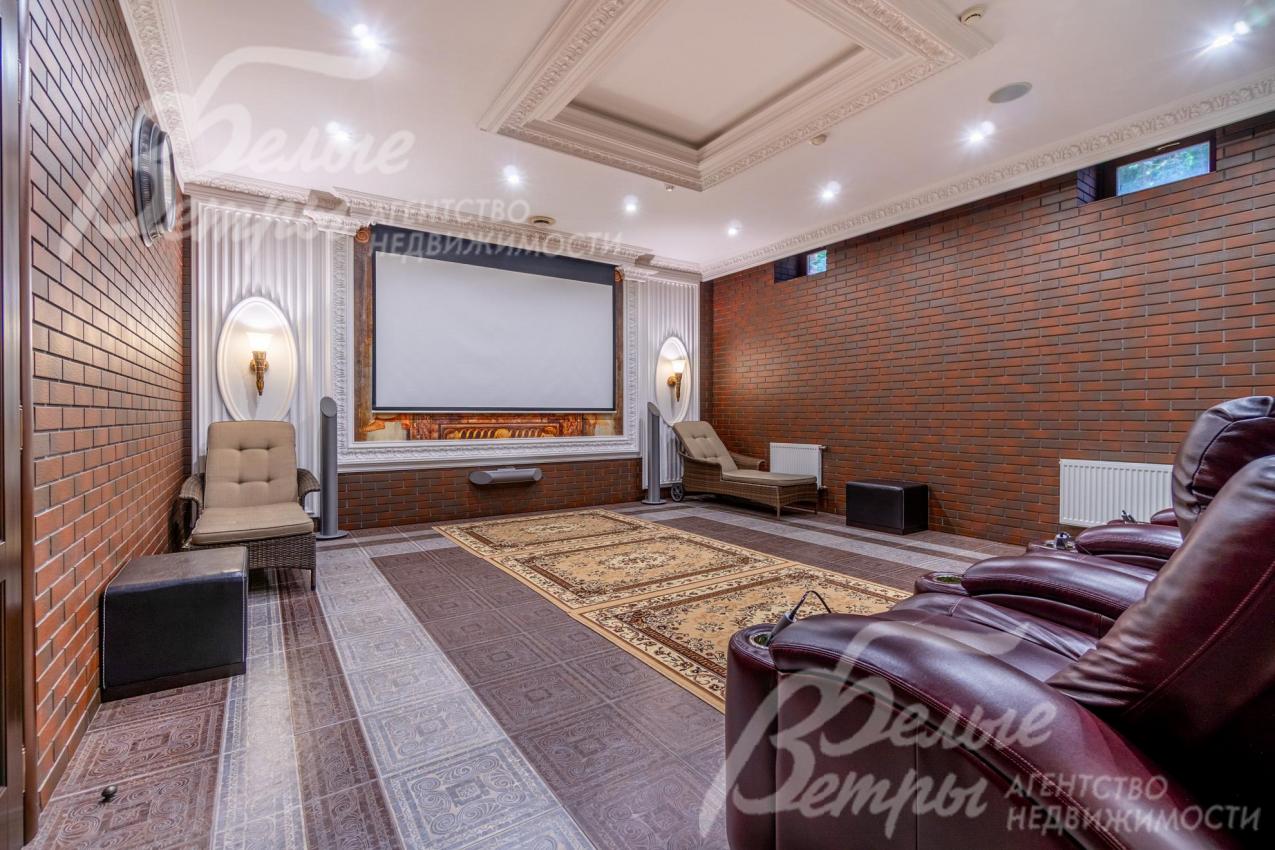 Просторный кинотеатр на цокольном этаже: установлены кресла  с реклайнерам, экран шириной 2,75 м