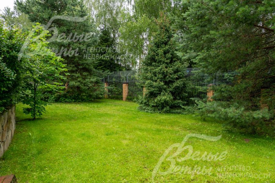 На участке выполнен проект паркового ландшафтного дизайна: высажен газон, взрослые хвойные деревья