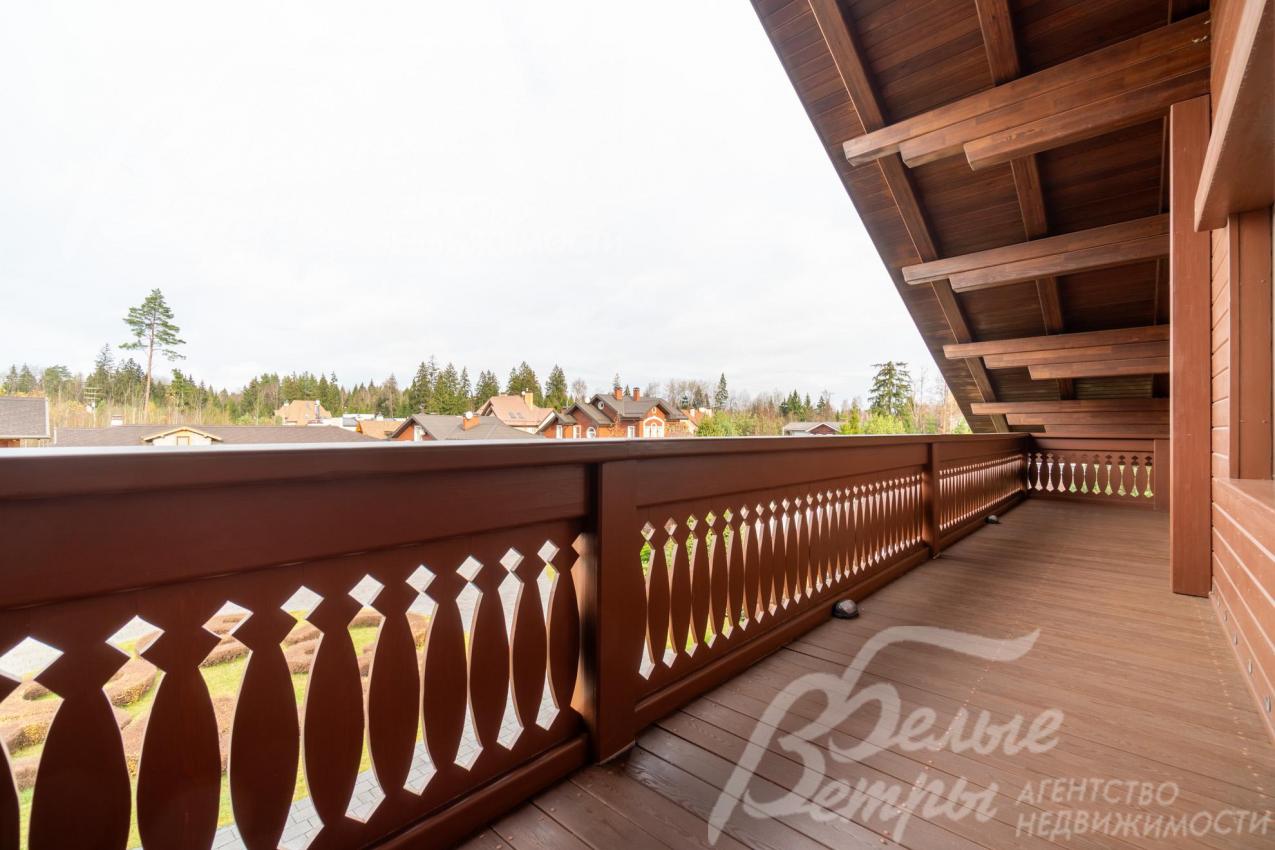 Лоджия мастер-спальни в стиле шале с резными деревянными перилами и тёплыми коричневыми оттенками