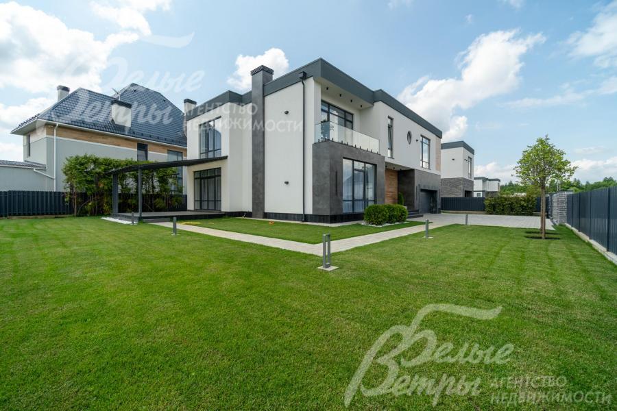 Дом стоит на зелёном участке с оформленным ландшафтом 