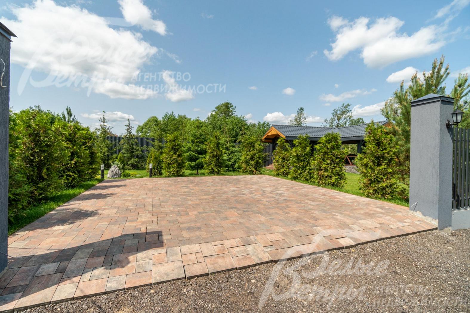 На въезде в дом - широкая парковка для двух автомобилей, выложена брусчаткой на бетонной основе, установлены откатные ворота
