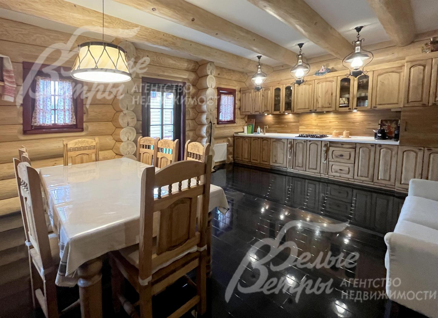 В зоне гостиной-столовой установлен гарнитур из массива дерева со встроенной техникой и столовая группа