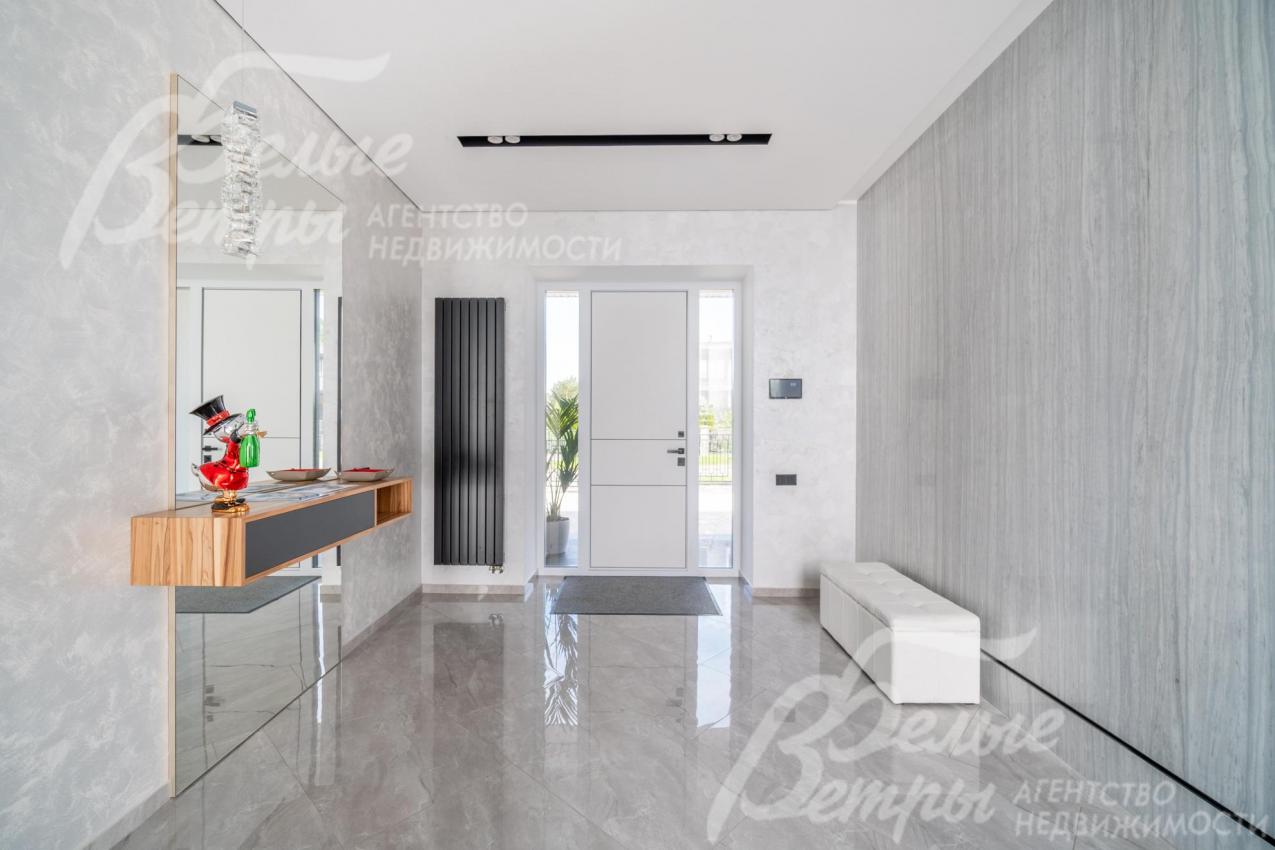 Просторный холл в светло-серых оттенках, на полу - широкоформатный керамогранит - мрамор с водяным подогревом