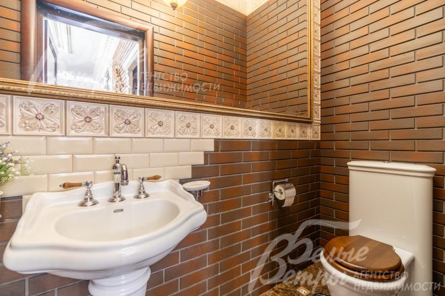 Гостевой санузел на первом этаже с большим зеркалом, стены отделаны клинкерной плиткой