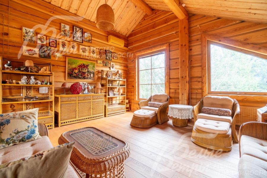 Гостиная на мансарде оснащена удобной мебелью, из окон - вид на лес