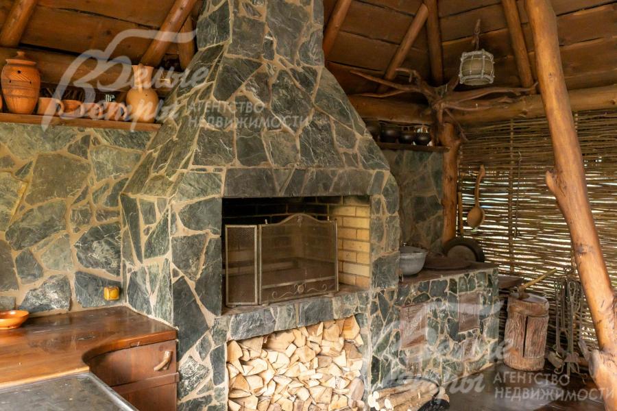 Впечатляющий мангал из природного камня дополнен практичной дровницей