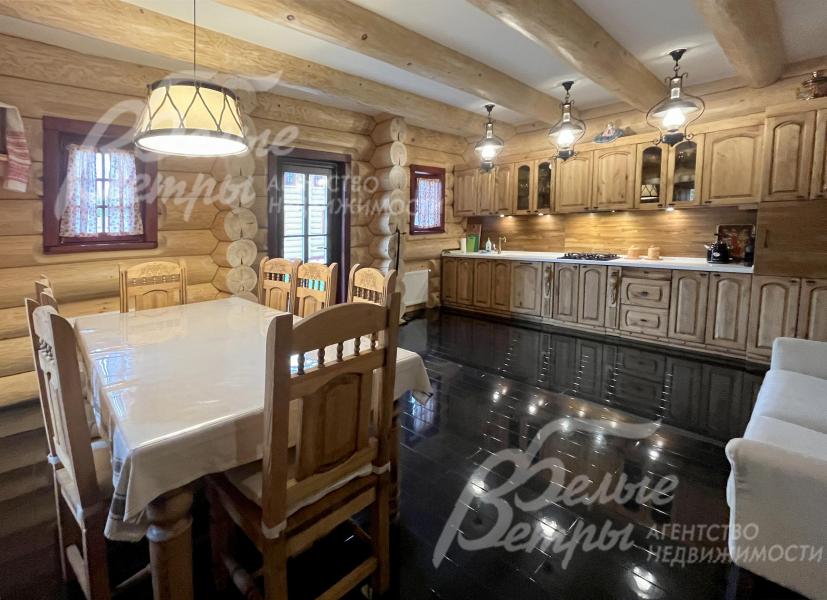 В зоне гостиной-столовой установлен гарнитур из массива дерева со встроенной техникой и столовая группа