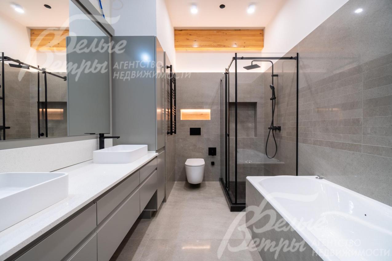 Санузел на втором этаже с ванной оформлен крупноформатной керамогранитной плиткой под камень в серых оттенках