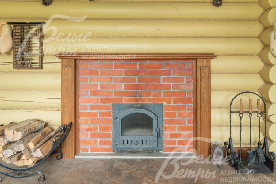 Печь в кирпичной кладке, рядом - дровница и каминный набор