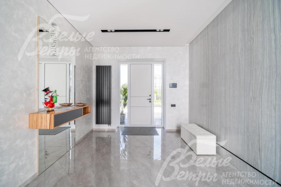 Просторный холл в светло-серых оттенках, на полу - широкоформатный керамогранит - мрамор с водяным подогревом