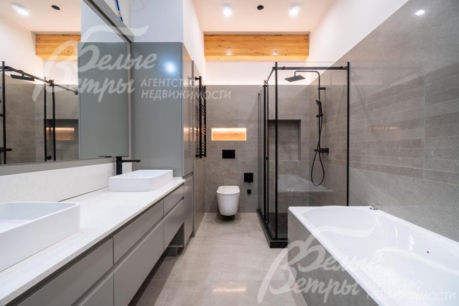 Санузел на втором этаже с ванной оформлен крупноформатной керамогранитной плиткой под камень в серых оттенках