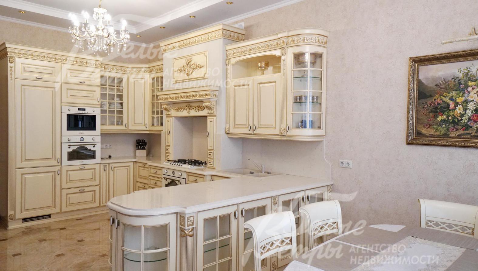 Кухня из дерева цвета молока с бронзовой фурнитурой и  золоченым декором, столешница из камня