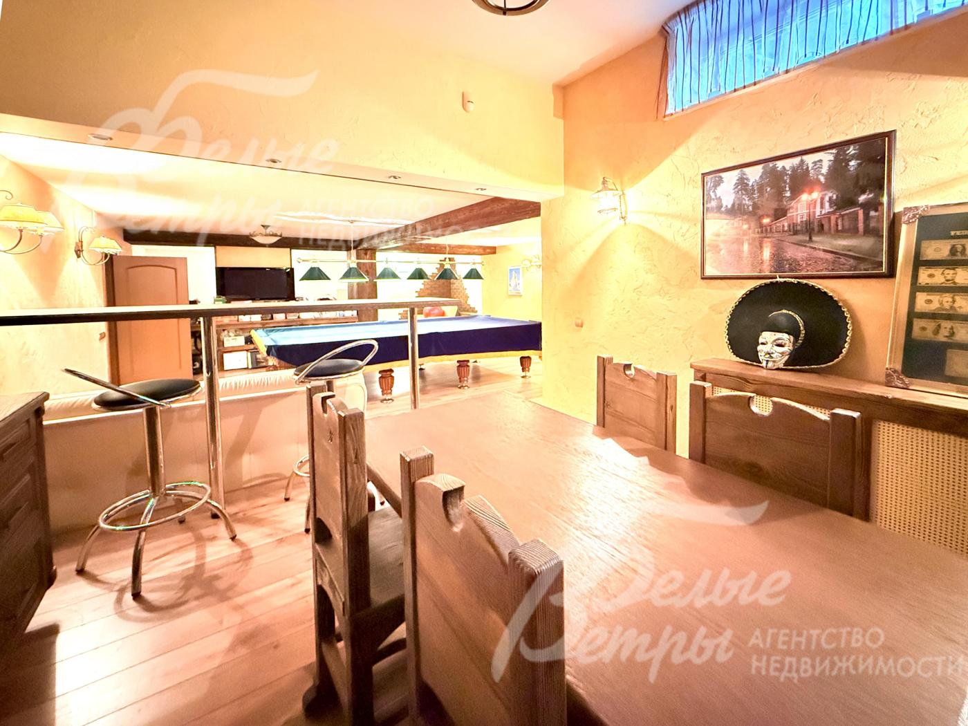 Рядом с бильярдной - комната отдыха (при сауне), расположенная на возвышенности, с деревянным столом и резными стульями