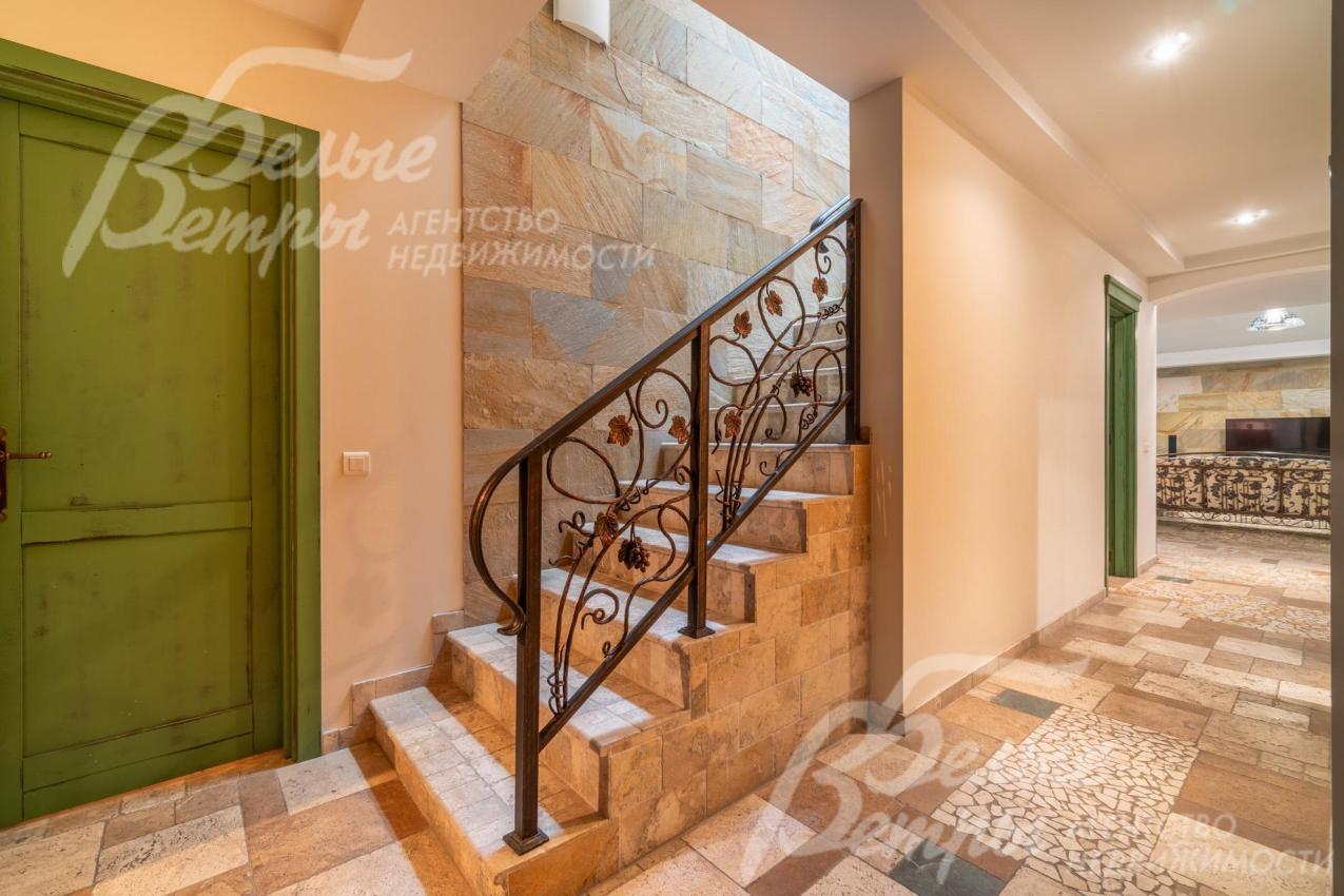 Лестница на железобетонном основании со ступенями, отделанными травертином, и перилами художественной ковки