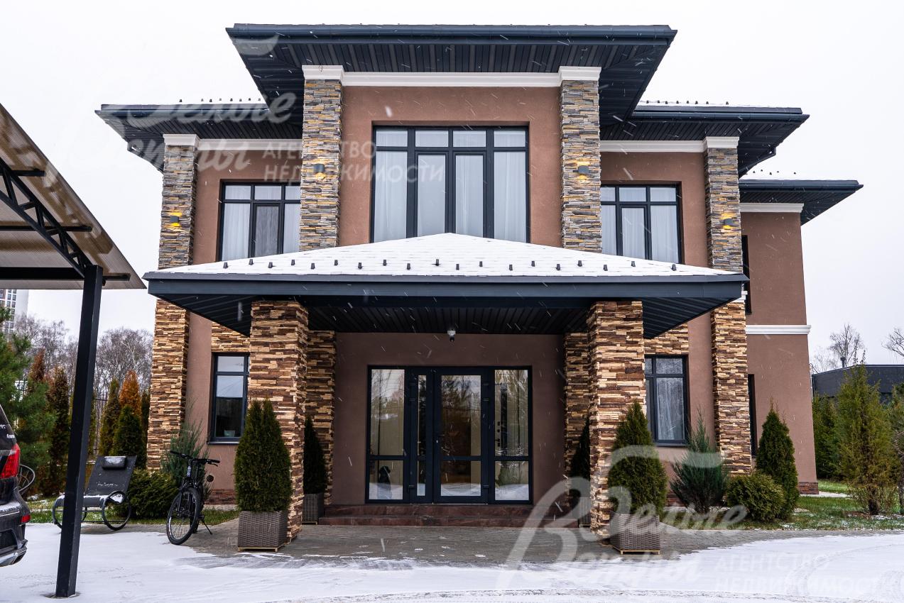Фасад дома выполнен в тёплых коричневых тонах, крыльцо украшают колонны