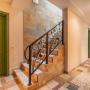 Лестница на железобетонном основании со ступенями, отделанными травертином, и перилами художественной ковки