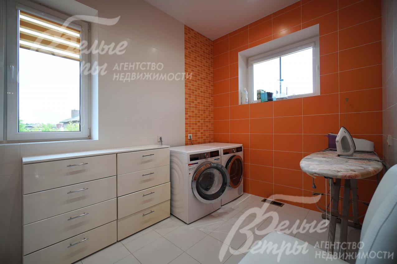 Постирочная на втором этаже со стиральной и сушильной машинами и гладильной доской